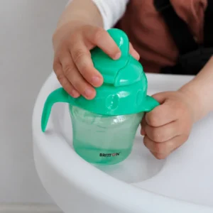 Child holding the Britton green non-spill cup in a high chair