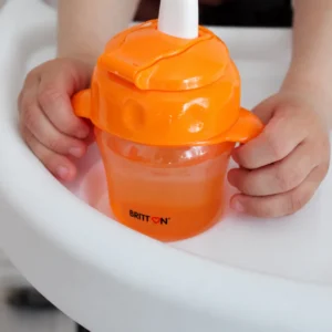 Close-up of a child holding the Britton orange non-spill cup