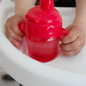 Close-up of a child holding the Britton red non-spill cup