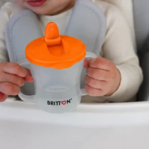 Child holding the Britton First Cup 200 ml orange